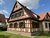 Historisches Fachwerkhaus bei Forchheim mit hellgelb gestrichenen Gefachen, rotbraun gefasstem Zierfachwerk und grünen Fensterläden
